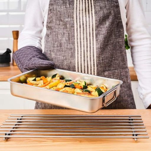 Person holding IKEA KONCIS stainless steel roasting tin filled with colourful roasted vegetables on kitchen counter
