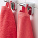 A close-up image of a folded red hand towel with a textured pattern and simple, classic hand towel, perfect for every bathroom 00439430