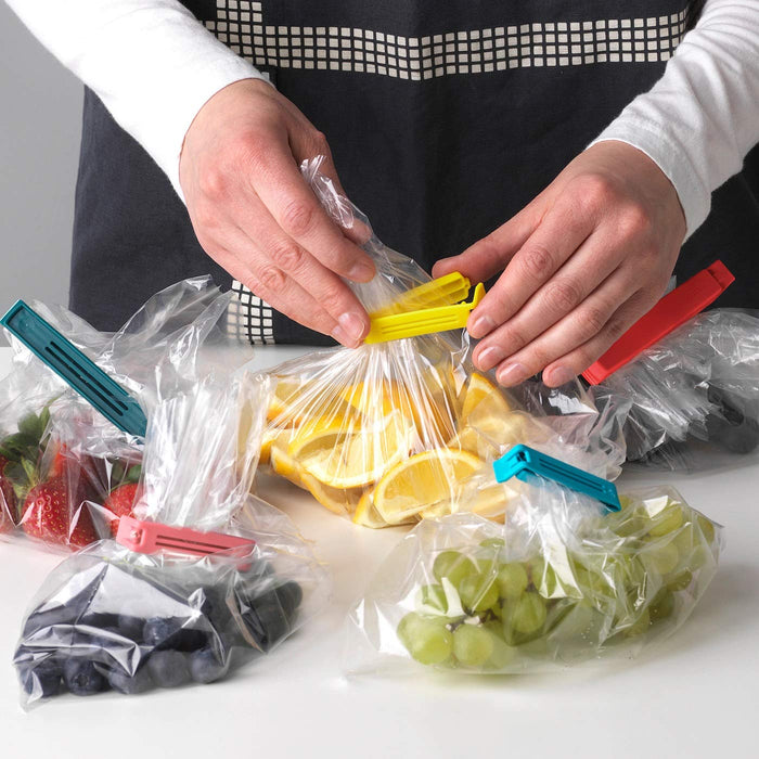A  girl using an IKEA sealing clip to close a bag of fruits 90339172