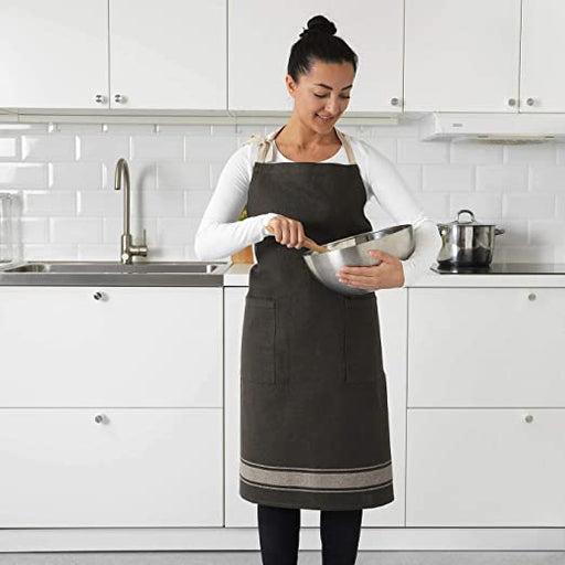 A female wearing a grey apron and holding a mixing bowl  70292627