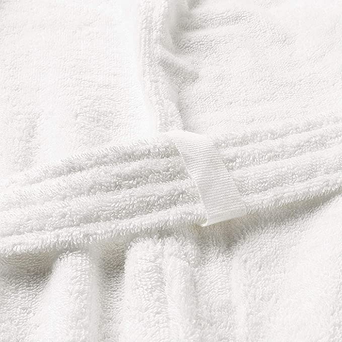 A folded white bathrobe on a shelf with other folded towels and linens in a closet.