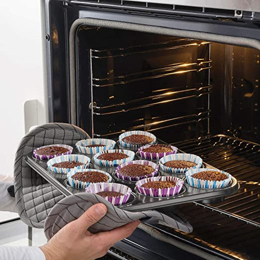An image of an IKEA Muffin Tin being placed in a preheated oven, ready to bake delicious muffins. The oven door is open and the rack is pulled out, showing the hand placing the muffin tin on the rack. The oven light is on and the interior is visible 50456691 