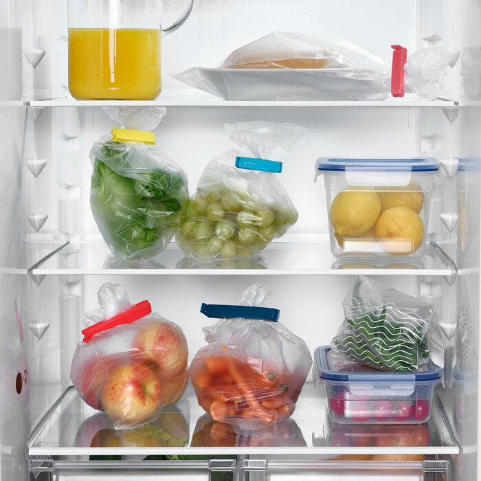 An IKEA sealing clip attached to a plastic bag of vegetables, which is placed inside a fridge 90339172
