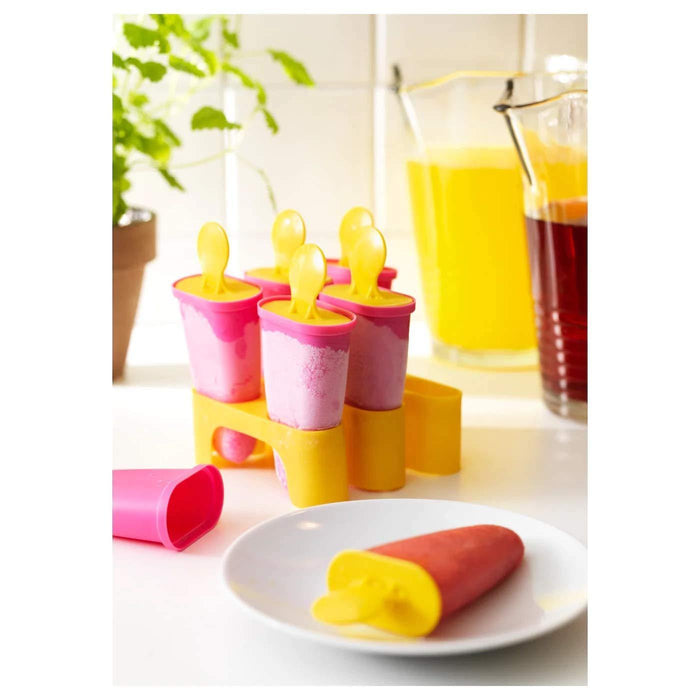 A close-up of an IKEA silicone popsicle mold, with a red handle and lid, filled with bright green kiwi and honeydew melon fruit juice.-60208479