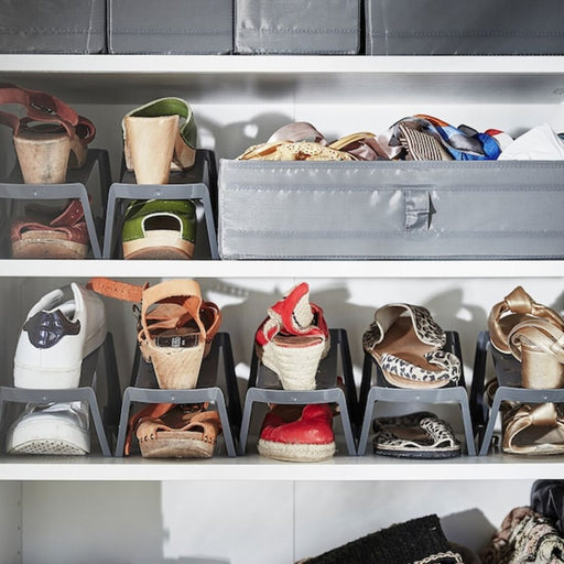 A pair of shoes being placed into the IKEA Shoe Organiser, showing the efficient and space-saving storage capabilities of the product.