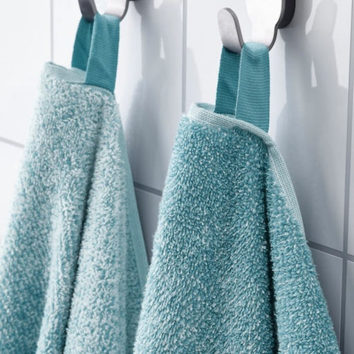 A hand reaching for a folded bath towel on a bathroom shelf. 50494315 