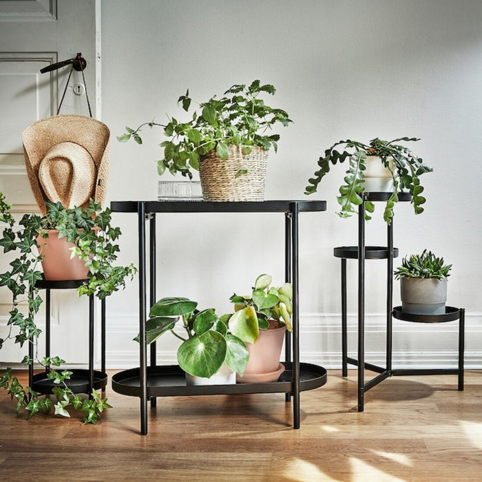 Digital Shoppy IKEA Plant stand, in/outdoor black, A black IKEA plant stand with a potted plant sitting on it, placed indoors in a living room.  30486651