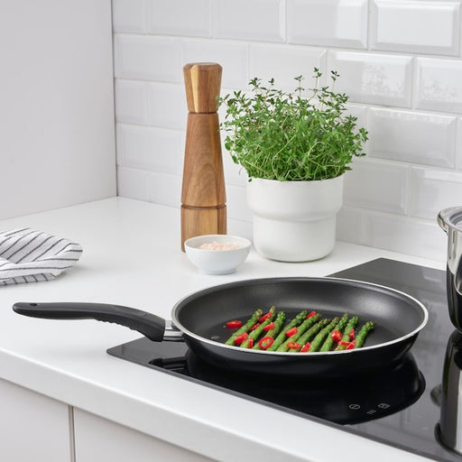 "The IKEA frying pan sitting on a stovetop with steam rising from the food inside"