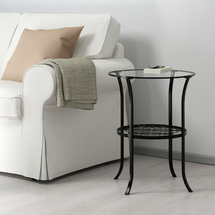 The Ikea side table in black/clear glass, placed next to a comfortable armchair in a modern living room.20161558