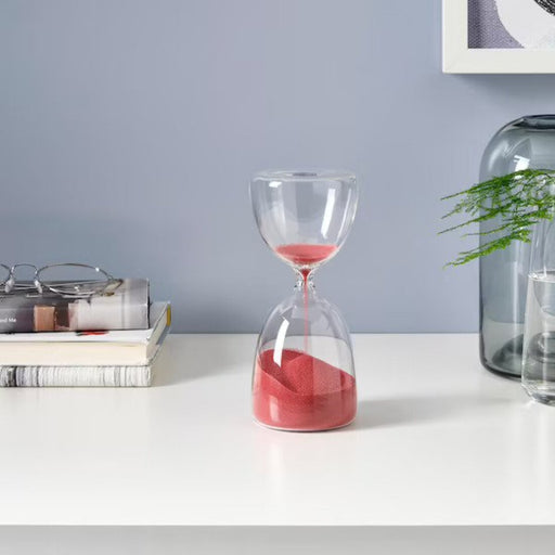 Hourglass on wooden table with sand flowing through - perfect decorative piece for home.