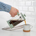 A guy pouring a coffee/tea intlo cup by using a coffee/tea maker 80515161