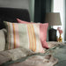  A image of an IKEA pink cushion cover with a multicolor/striped pattern on a bed-20513631