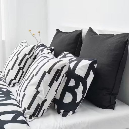 Multiple IKEA cushion covers in different colors and designs on a bed-10443592