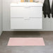 Pale-pink bath mat placed on a bathroom floor, featuring a soft and absorbent texture and a non-slip bottom for secure footing 40511363