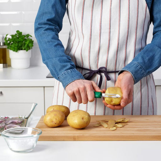 An image of an IKEA potato peeler in use, as it peels the skin off a potato with ease 00521953