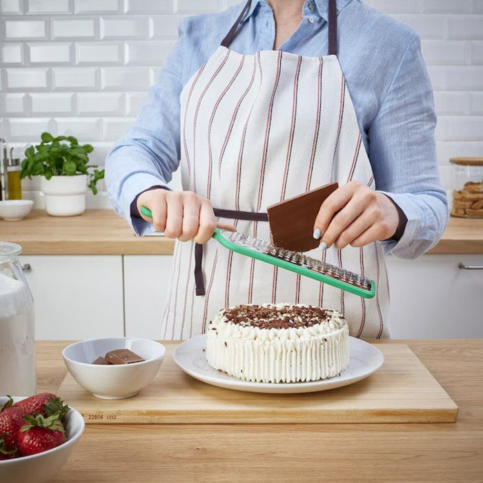 A person's hand using the IKEA Grater with Handle to grate a block of chocolate 30160964