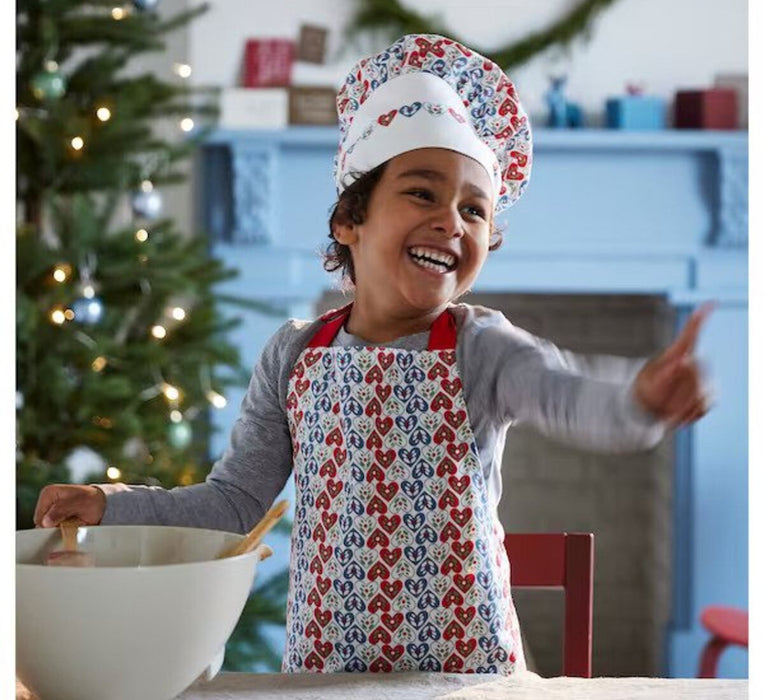 A young child wearing a chef's hat and apron, holding a mixing bowl and spoon 60484047