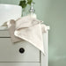A natural IKEA hand towel with a natural stripe pattern folded neatly on a green  table. 90512510