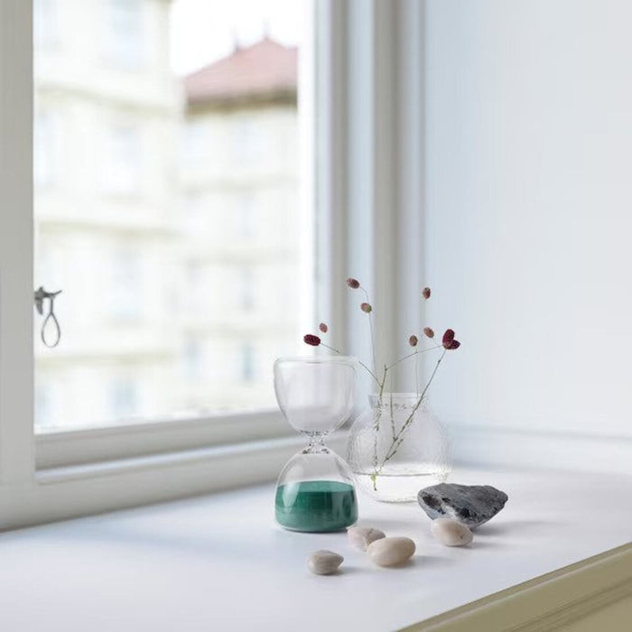 A clear glass hourglass with white sand inside, ideal for adding a sophisticated touch to home or office decor