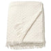 A plush, white faux-fur throw with a silky smooth underside, thrown over the back of a velvet armchair.-00529096