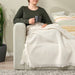 A plush, white faux-fur throw with a silky smooth underside, thrown over the back of a velvet armchair.-00529096