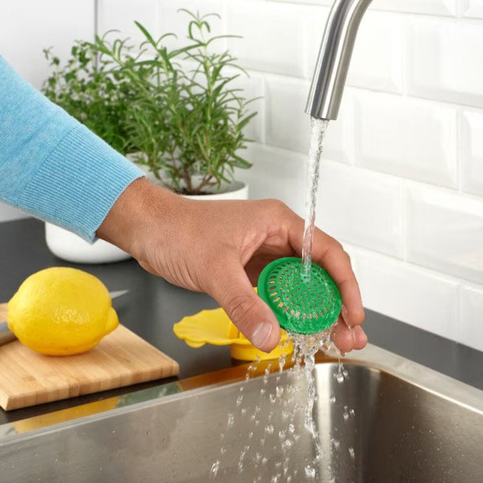 A hand holding the IKEA Lemon Squeezer under running water, highlighting its easy-to-clean and low-maintenance design 70528692