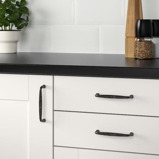 A minimalist black handle on an IKEA kitchen cabinet, adding a modern touch to the sleek design 00270068