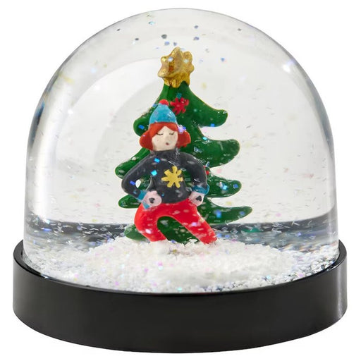 A snow globe featuring a miniature version of a bedroom scene, with a bed, nightstand, and lamp surrounded by swirling snow.