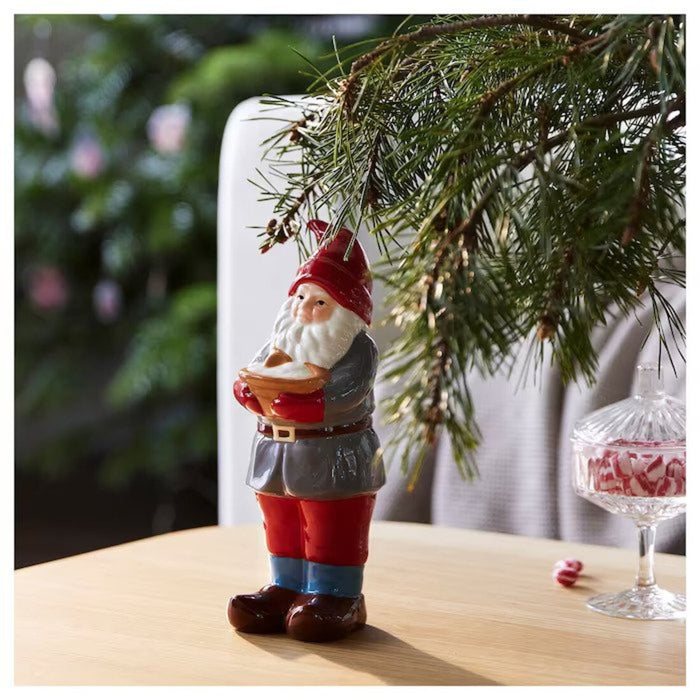 A Santa Claus figurine sitting on a mantel with stockings and other Christmas decorations.