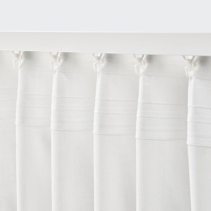 Plain white linen curtains hanging straight and simple in a minimalist living room.-40491039
