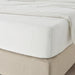 A closeup image of IKEA fitted sheet on a bed with neatly tucked corners and a smooth surface  90347681