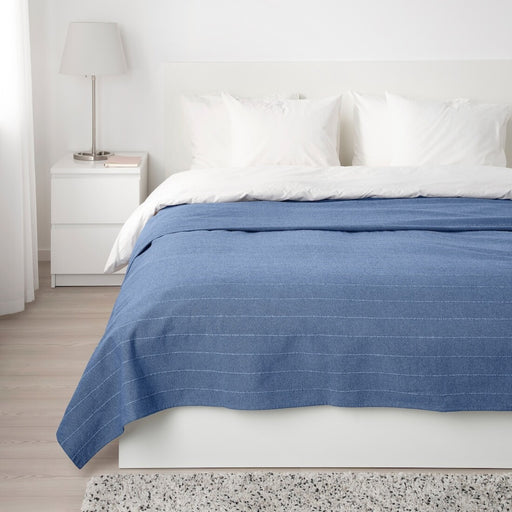 A modern bedspread with coordinating decorative pillows, spread across a crisp white bed.
