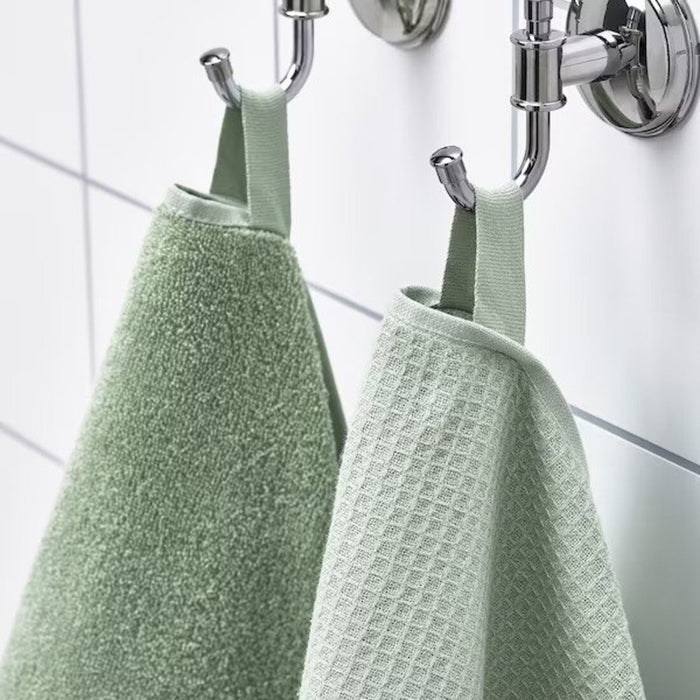 A close-up image of a simple and classic light green hand towel hanging on a bathroom hook 90512548 