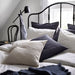 Multiple IKEA cushion covers in different colors and designs on a bed-40456540