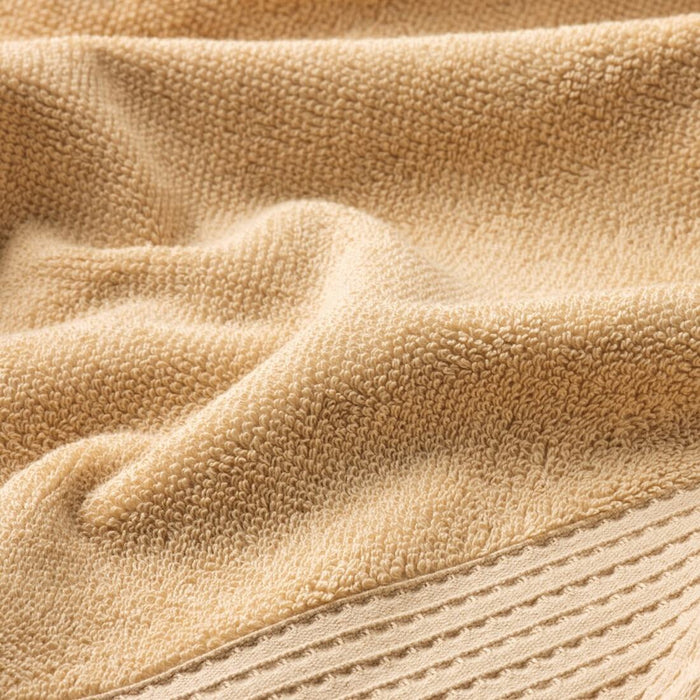 A plush light yellow towel, 70x140 cm, laid out on a bathroom countertop.40508332