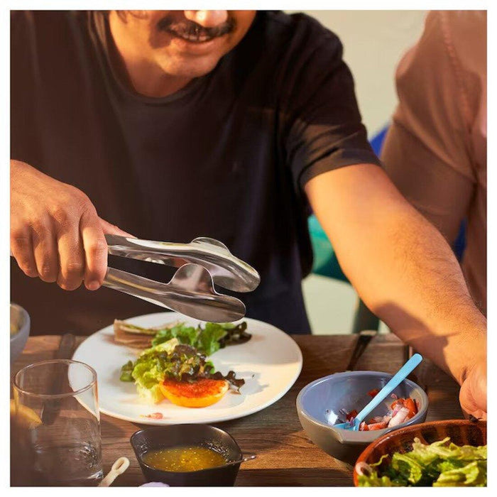 Digital Shoppy IKEA  close-up of a stainless steel serving tong's wide, flat tips and textured grip handles.  60546093