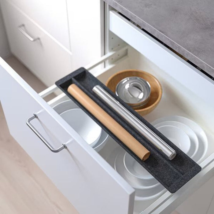 "The IKEA Sliding Organizer in Grey installed in a kitchen drawer, holding cutlery and utensils in its divided sections.