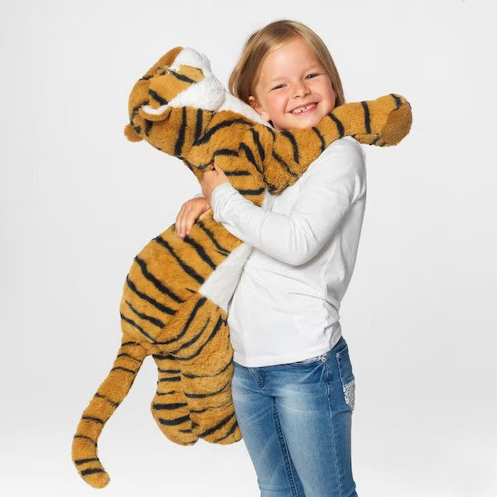A child holding IKEA's tiger soft toy, with a smile on their face-50408582