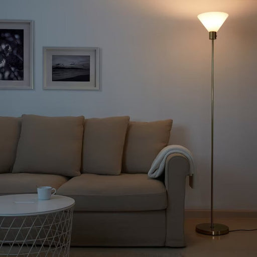 Modern floor lamp with a brass base and a frosted glass shade, creating an ambient atmosphere 40463456               