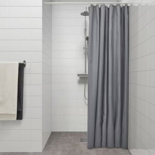 A long,dark gray shower curtain from IKEA that extends to the floor, creating a luxurious and spa-like feel in the bathroom. 
