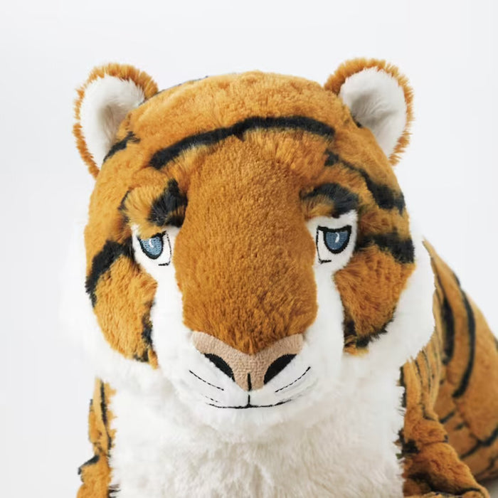 An adult sitting on a couch with IKEA's tiger soft toy, looking relaxed and happy.-50408582