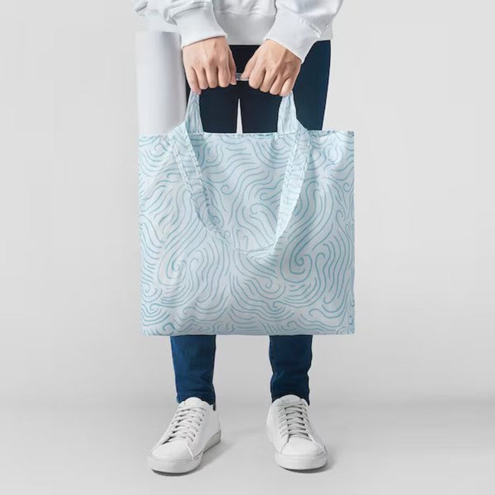 A person carrying a full bag of groceries in the iconic blue and white IKEA carrier bag with comfortable handles 40544392