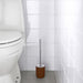 The brown toilet brush standing in its holder, which is also brown and has a modern and minimalist design.