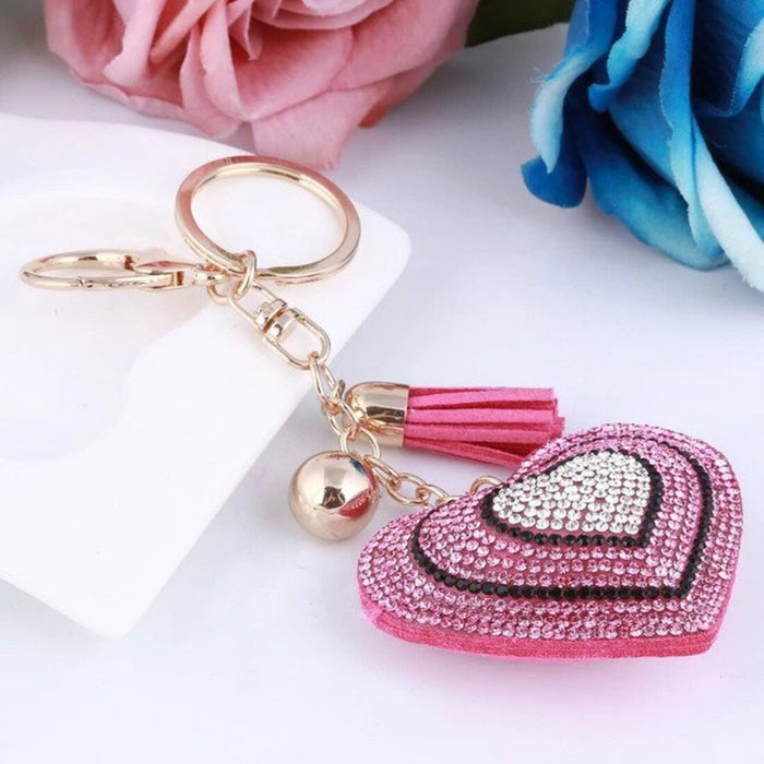 A silver-colored key chain with a sparkling crystal heart pendant