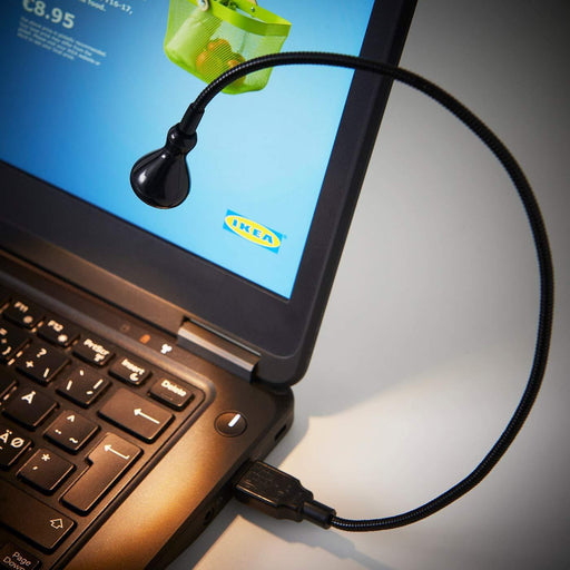 IKEA JANSJÖ black USB lamp plugged into laptop on a study desk warm white light
