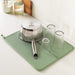 A dish rack placed on top of a dish drying mat, with various dishes, cups, and utensils placed on top to dry 60451061