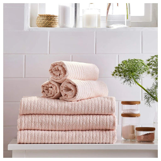 A  pale pink IKEA hand towel a It is folded neatly and placed on a wooden surface