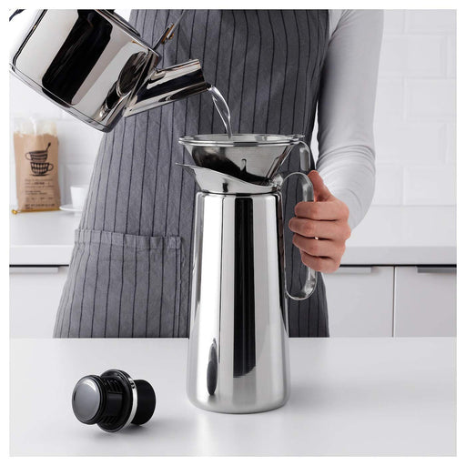 A silver metal pour-over kettle with a long spout, used for precision pouring of hot water.
