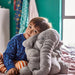 The IKEA Soft Toy Elephant in a playful pose, with its trunk lifted high and its ears perked up.