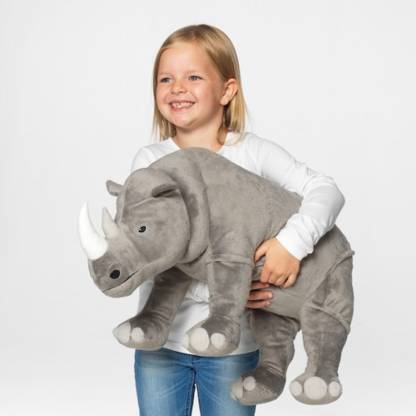 The IKEA Soft Toy Rhino sitting on a shelf, surrounded by other stuffed animals and toys.
